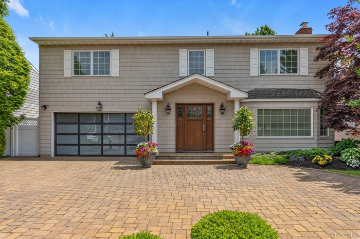 Two-story residence siding, a prominent wood entry door with sidelights, and a bay window