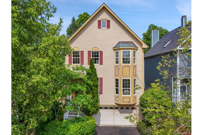 Traditional Contemporary-style exterior featuring light-colored siding, a prominent bay window, and red window shutters