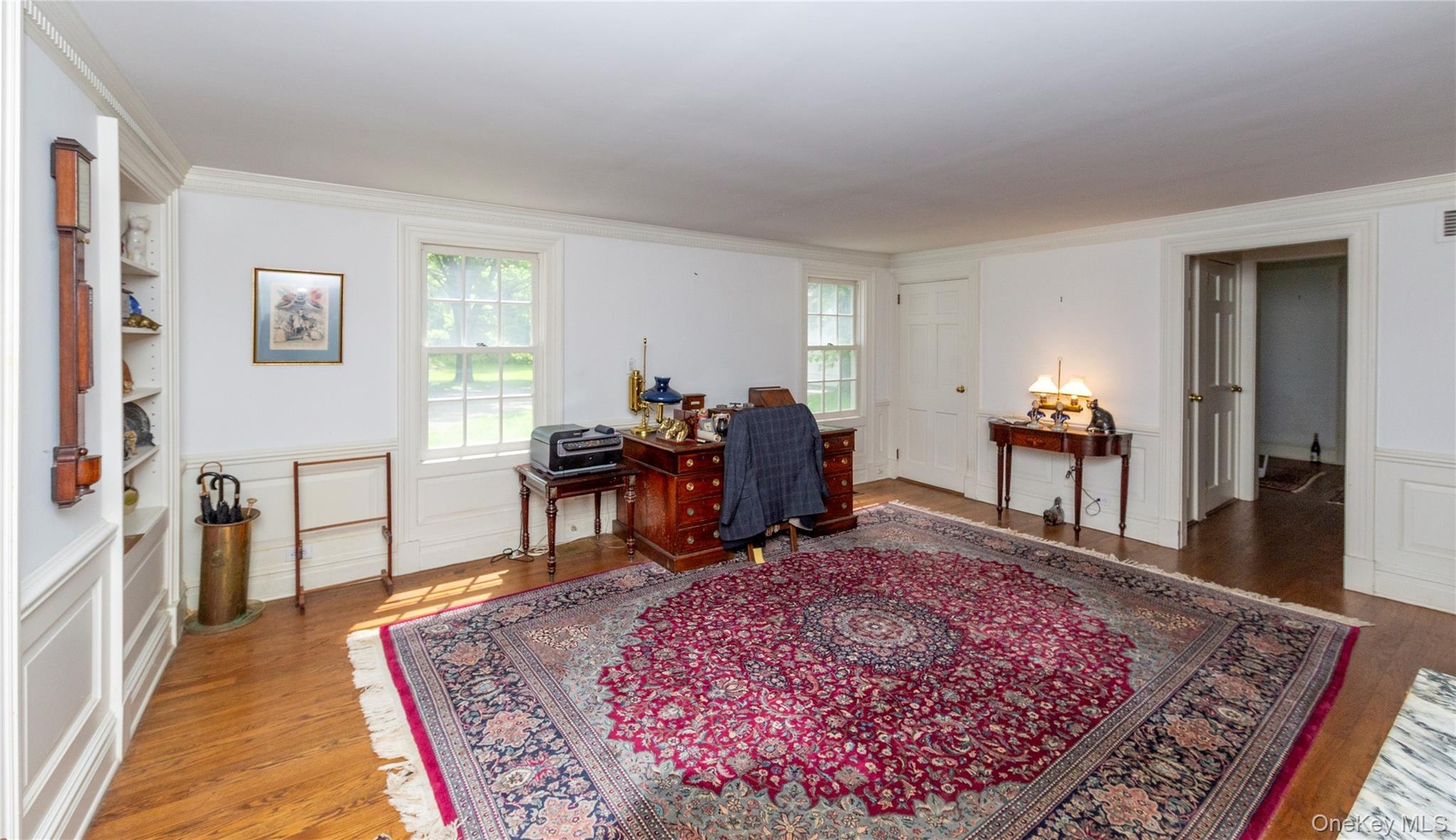 Spacious interior room featuring hardwood flooring and white paneled walls
