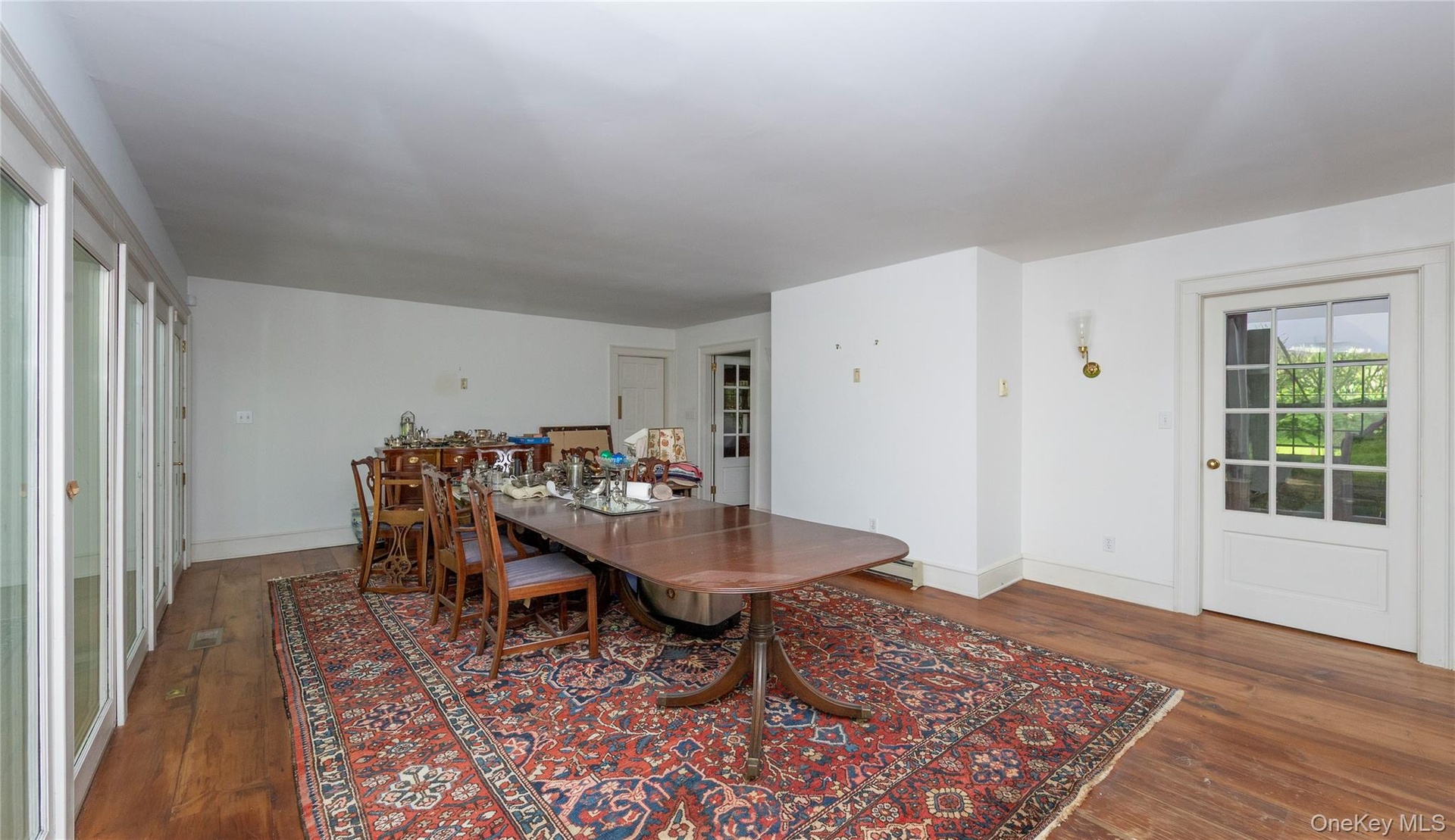 Spacious Dining room featuring wood-finish flooring, white walls, and a wall of multiple glass-paned doors