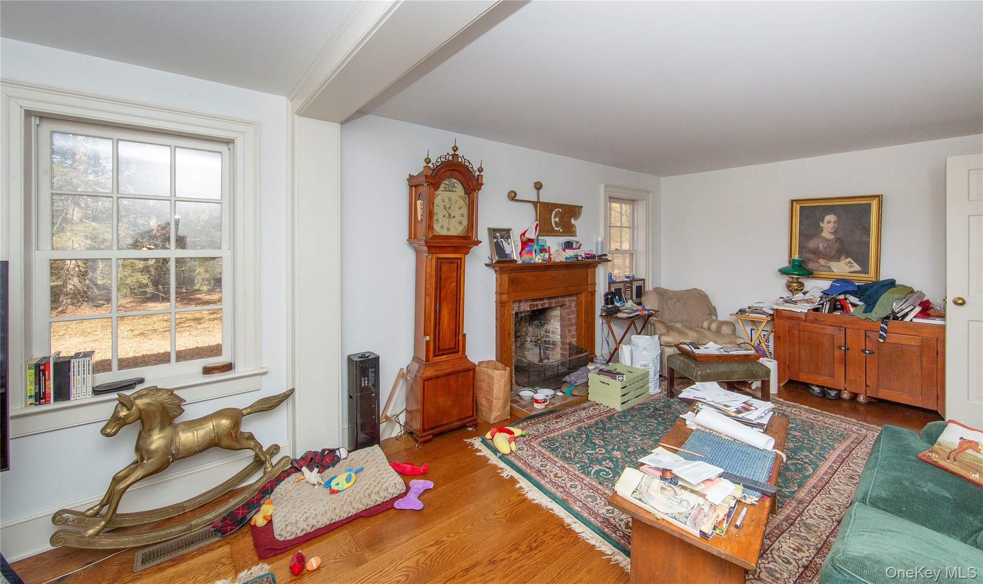 Hardwood flooring throughout a room featuring a brick fireplace with a wood mantel
