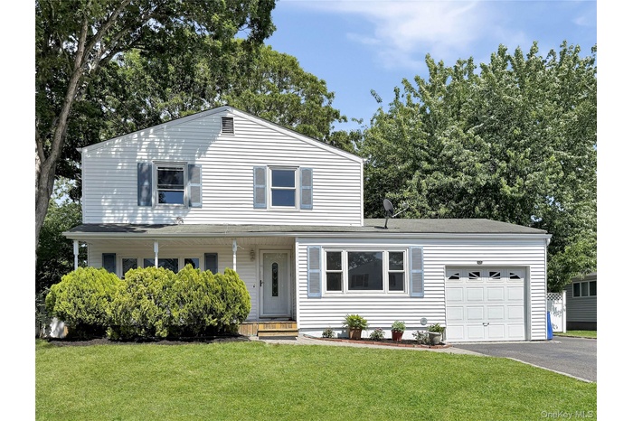 White siding exterior with blue window shutters, featuring a covered front porch, an attached garage, a paved driveway