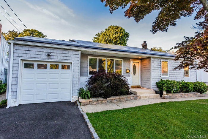 Ranch-style exterior featuring gray shake siding, a white panel garage door, and a white entry door with an oval glass insert