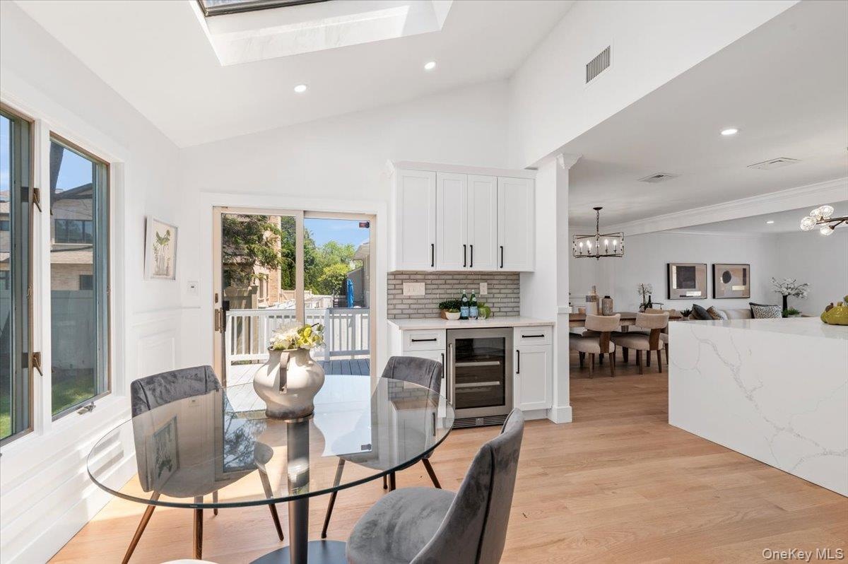 Dining space with wine cooler, a chandelier, recessed lighting, light wood-style floors, and vaulted ceiling