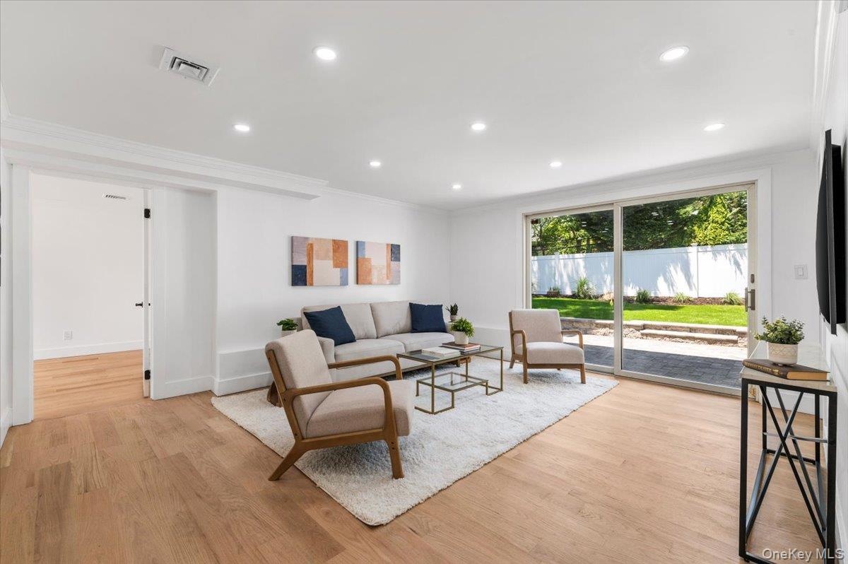 Living room with ornamental molding, light wood-style floors, and recessed lighting