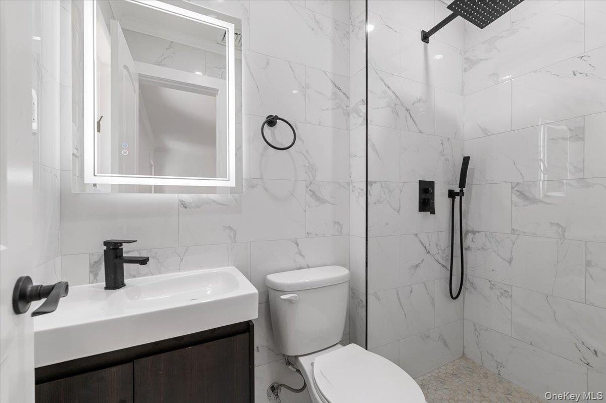 Full bath featuring a tile shower and vanity