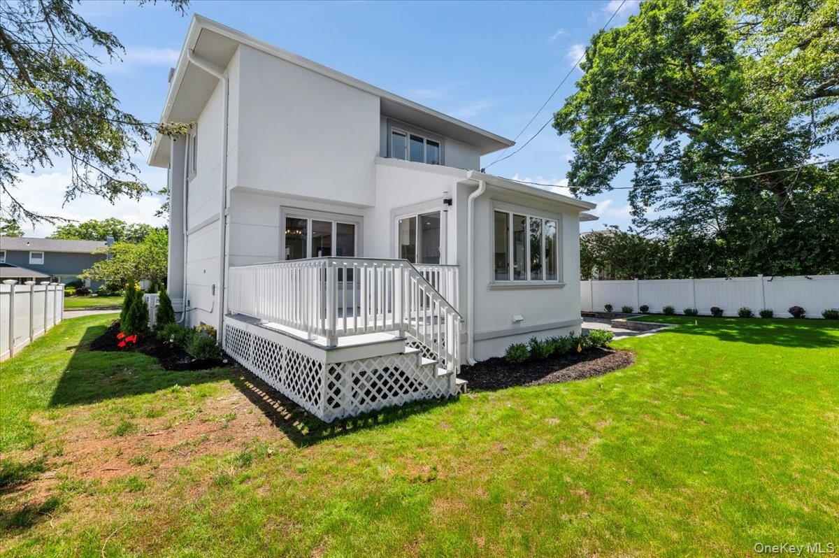 Rear view of property featuring a wooden deck and stucco siding