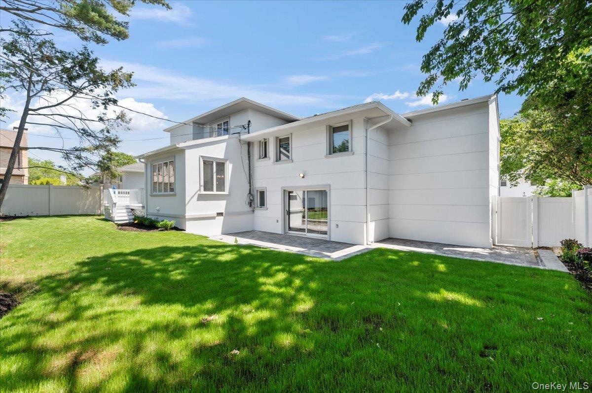 Rear view of house with stucco siding, a gate, and a patio area