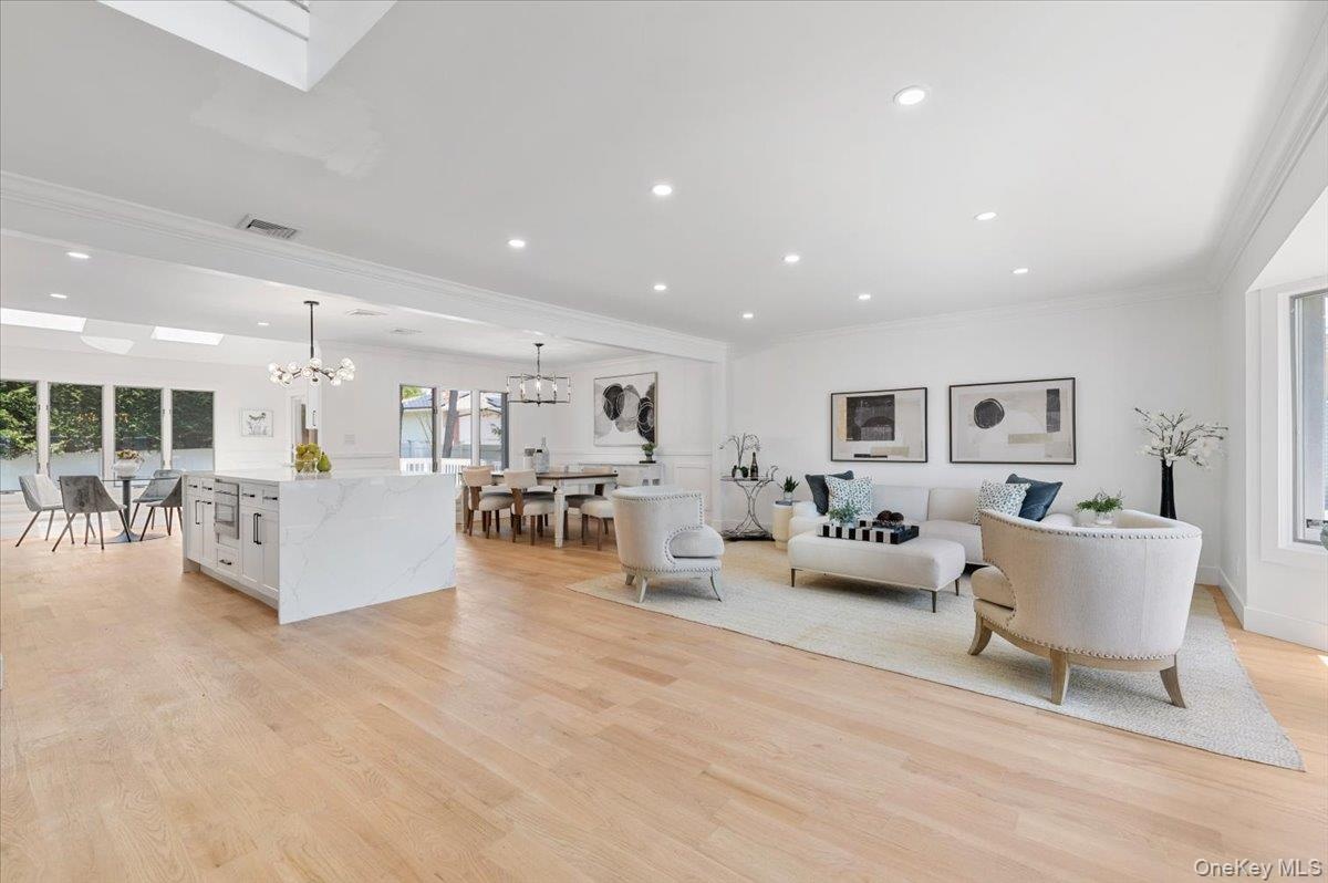 Living area featuring ornamental molding, a chandelier, light wood-style flooring, and recessed lighting