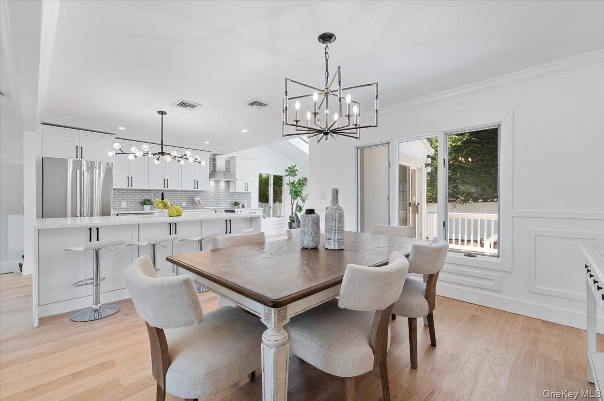 Dining area with a chandelier, light wood-style flooring, recessed lighting, and ornamental molding