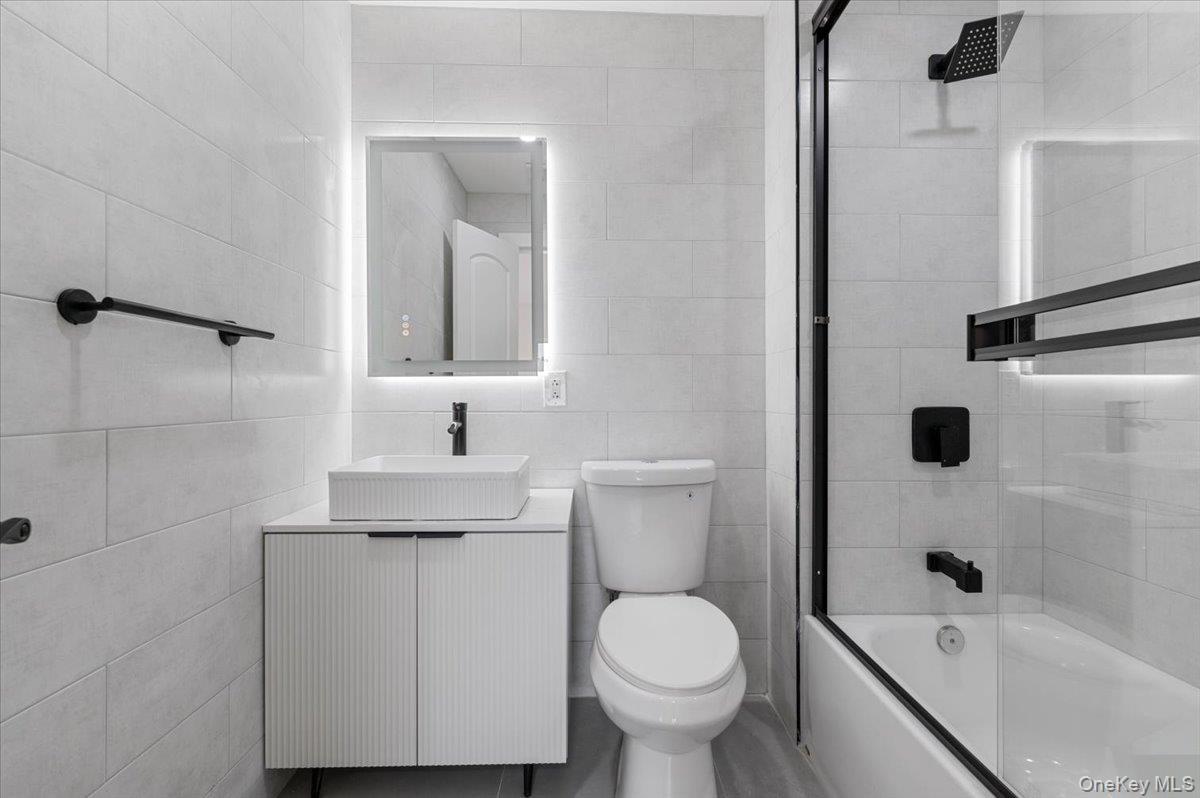 Bathroom featuring tile walls, bathing tub / shower combination, and vanity