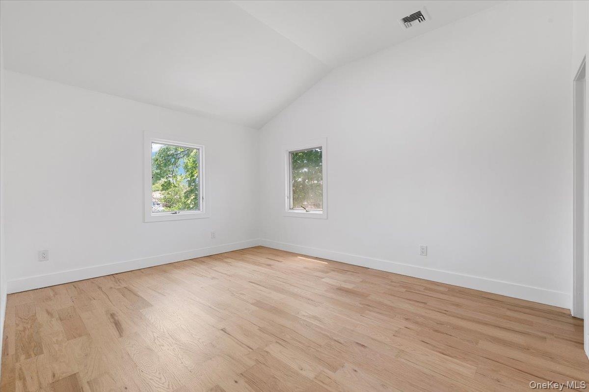 Unfurnished room with vaulted ceiling and light wood-type flooring