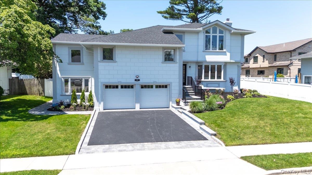 View of front of house featuring roof with shingles, driveway, an attached garage, and a chimney