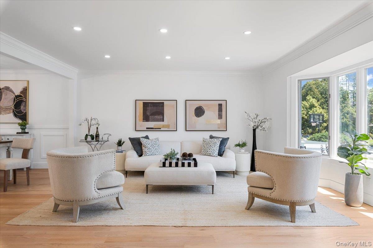 Living room featuring crown molding, light wood finished floors, recessed lighting, and wainscoting