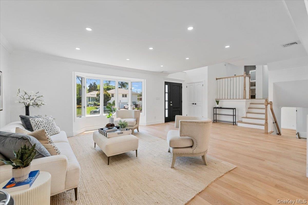 Living room with light wood-style flooring, stairs, recessed lighting, and ornamental molding
