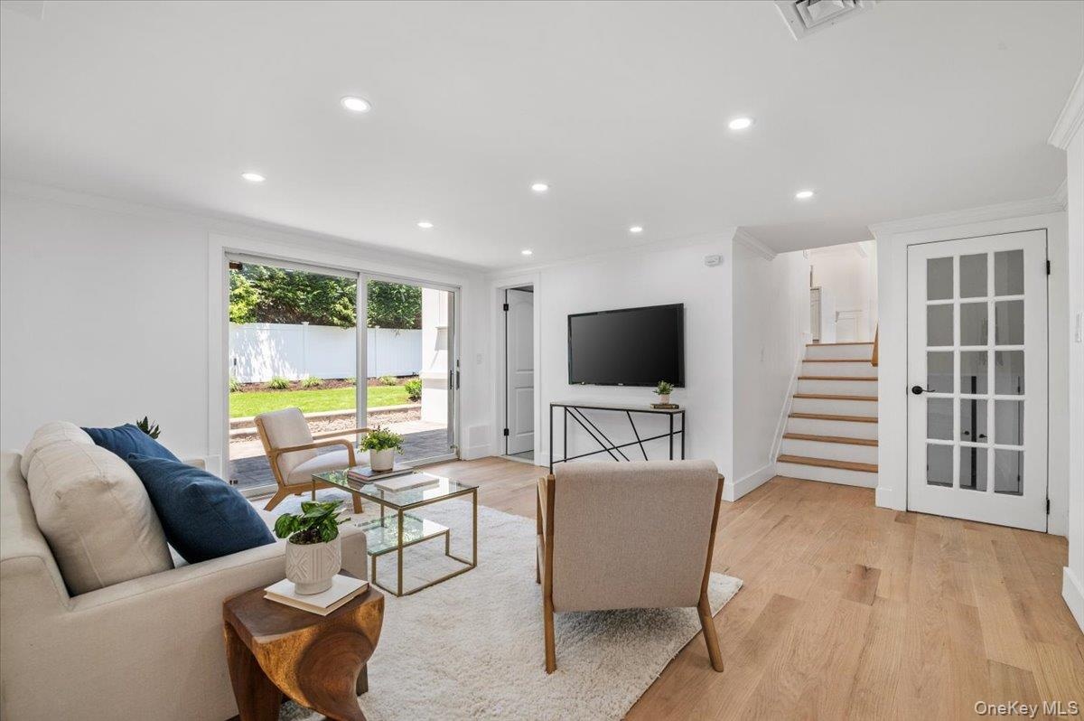 Living room with crown molding, recessed lighting, light wood finished floors, and stairway
