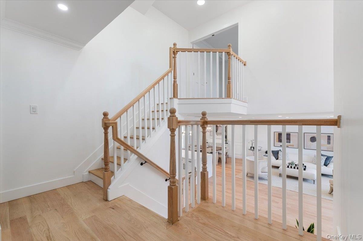 Stairs featuring wood finished floors, recessed lighting, a towering ceiling, and ornamental molding
