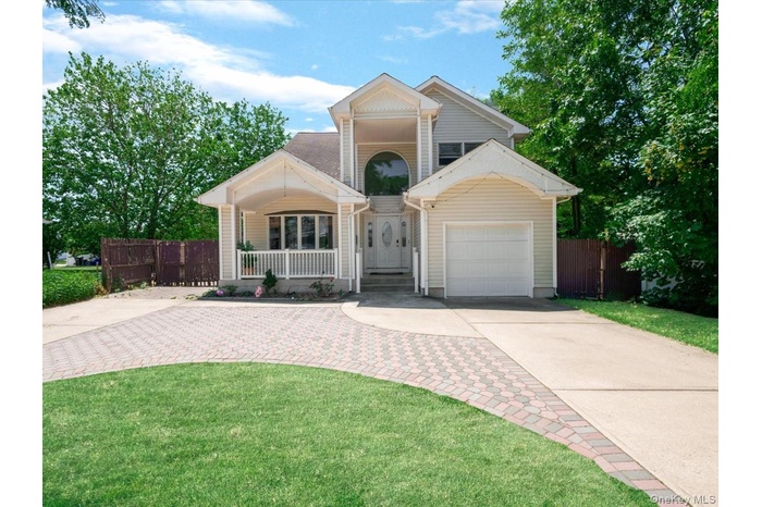 Multi-level residence featuring a prominent arched entry, a covered porch with white railings, and a single-car garage