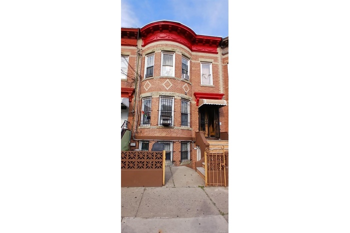 Brick townhouse featuring decorative architectural details, fenced front yard, and separate lower-level entrance.