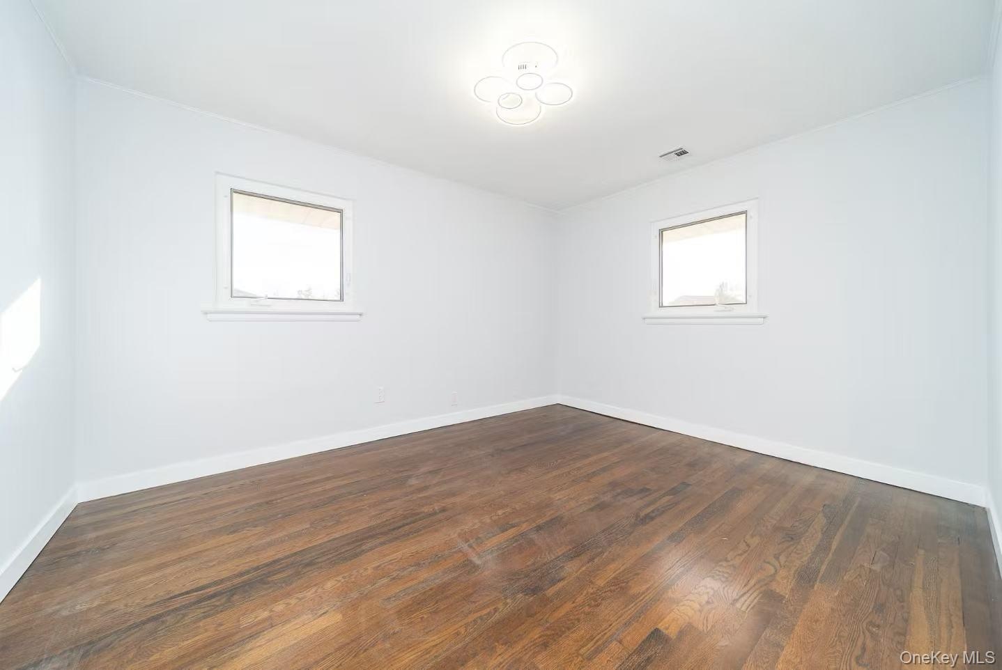 Spare room featuring dark wood finished floors and baseboards