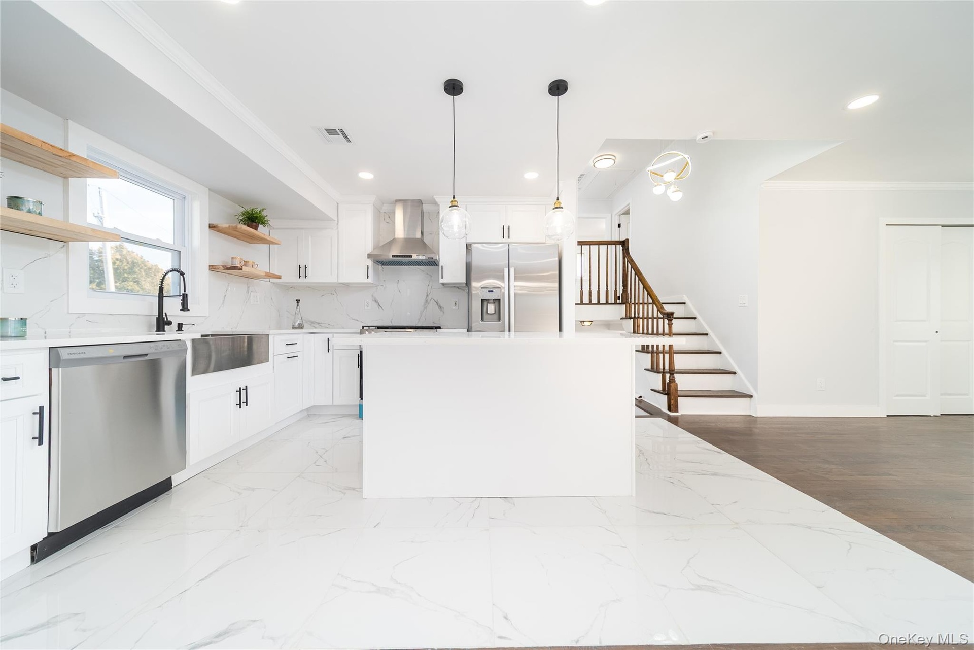 Kitchen with crown molding, white cabinetry, appliances with stainless steel finishes, a center island, and pendant lighting