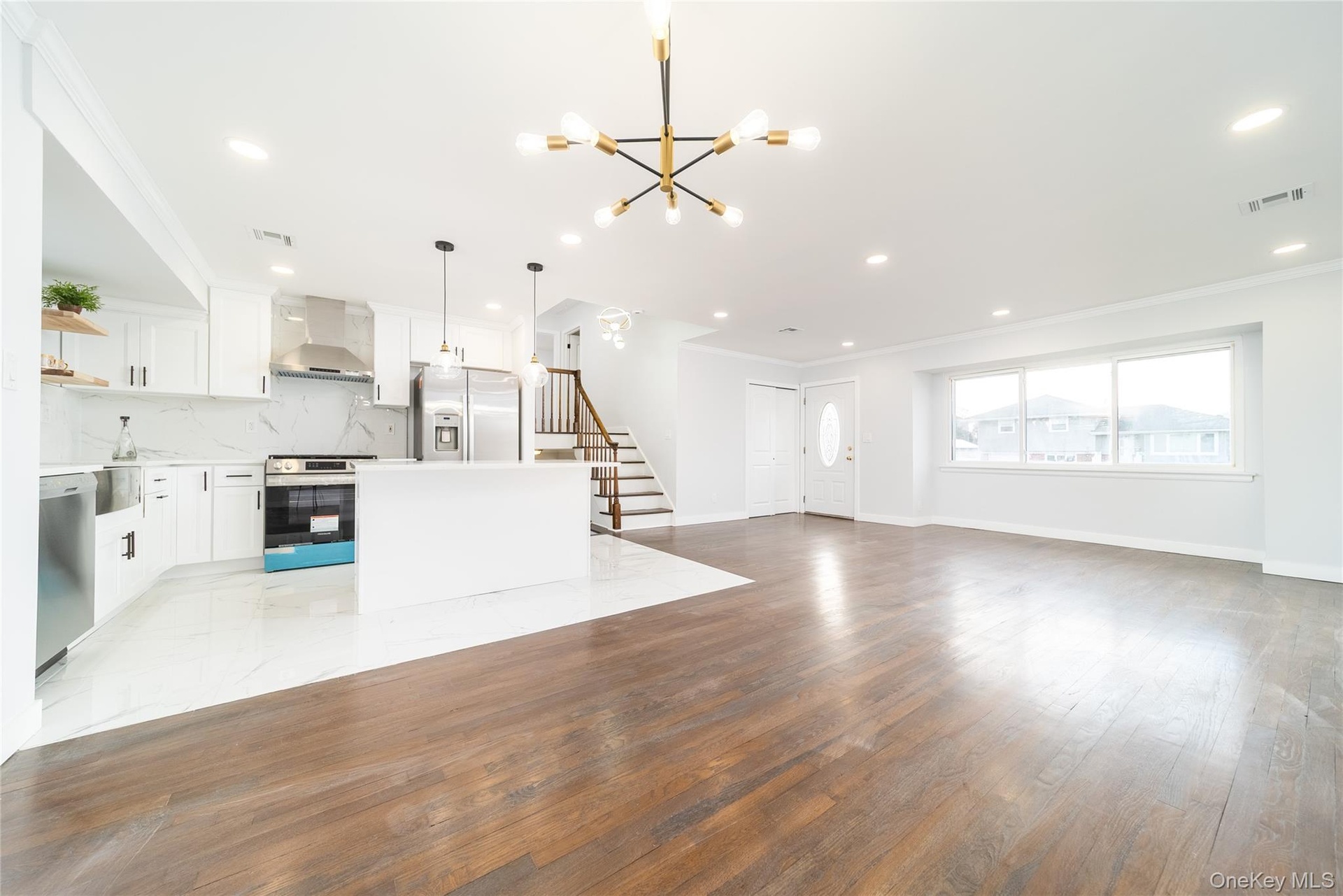 Unfurnished living room with ornamental molding, stairway, light wood-style floors, a chandelier, and recessed lighting