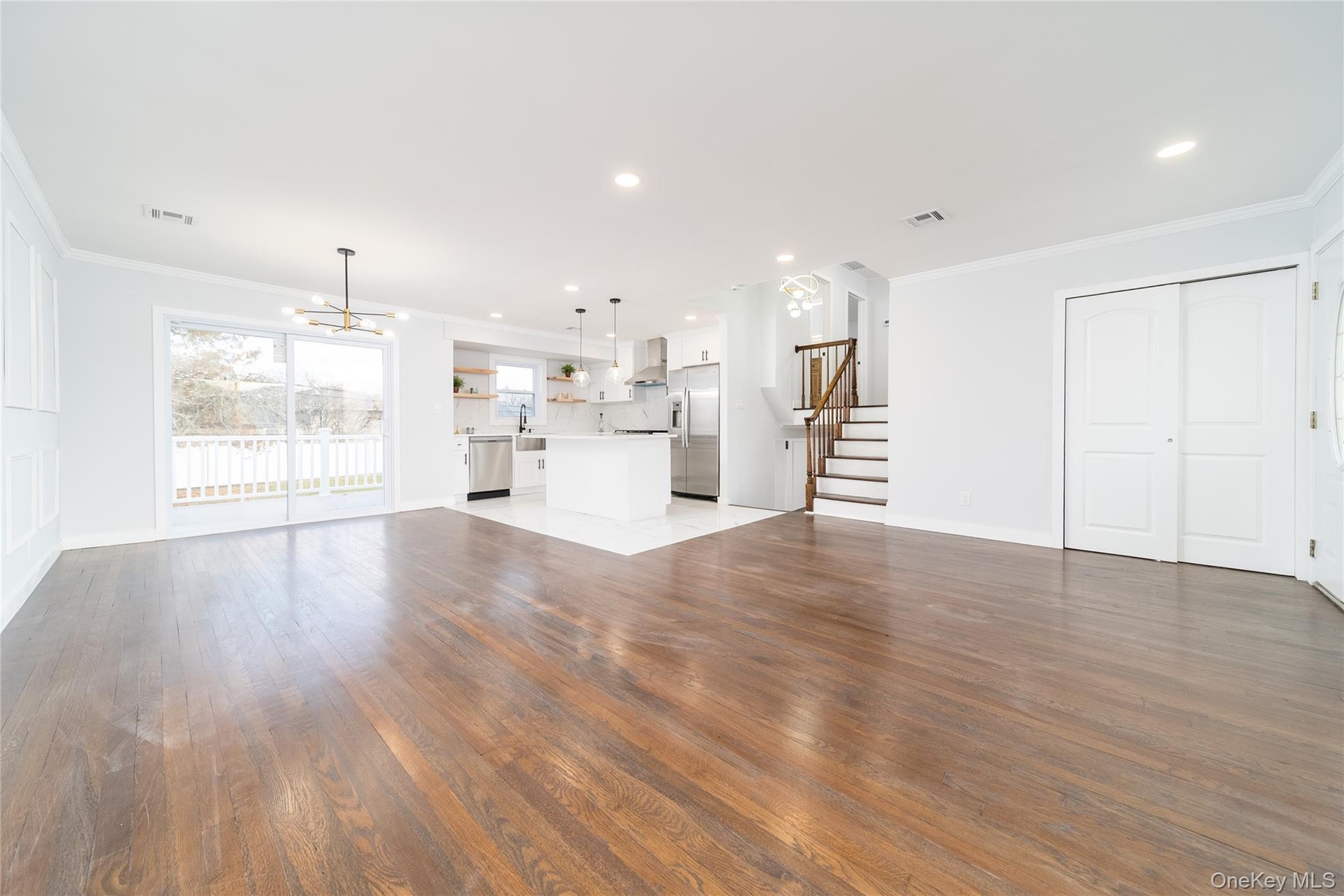 Unfurnished living room with crown molding, stairway, a chandelier, dark wood-style flooring, and recessed lighting