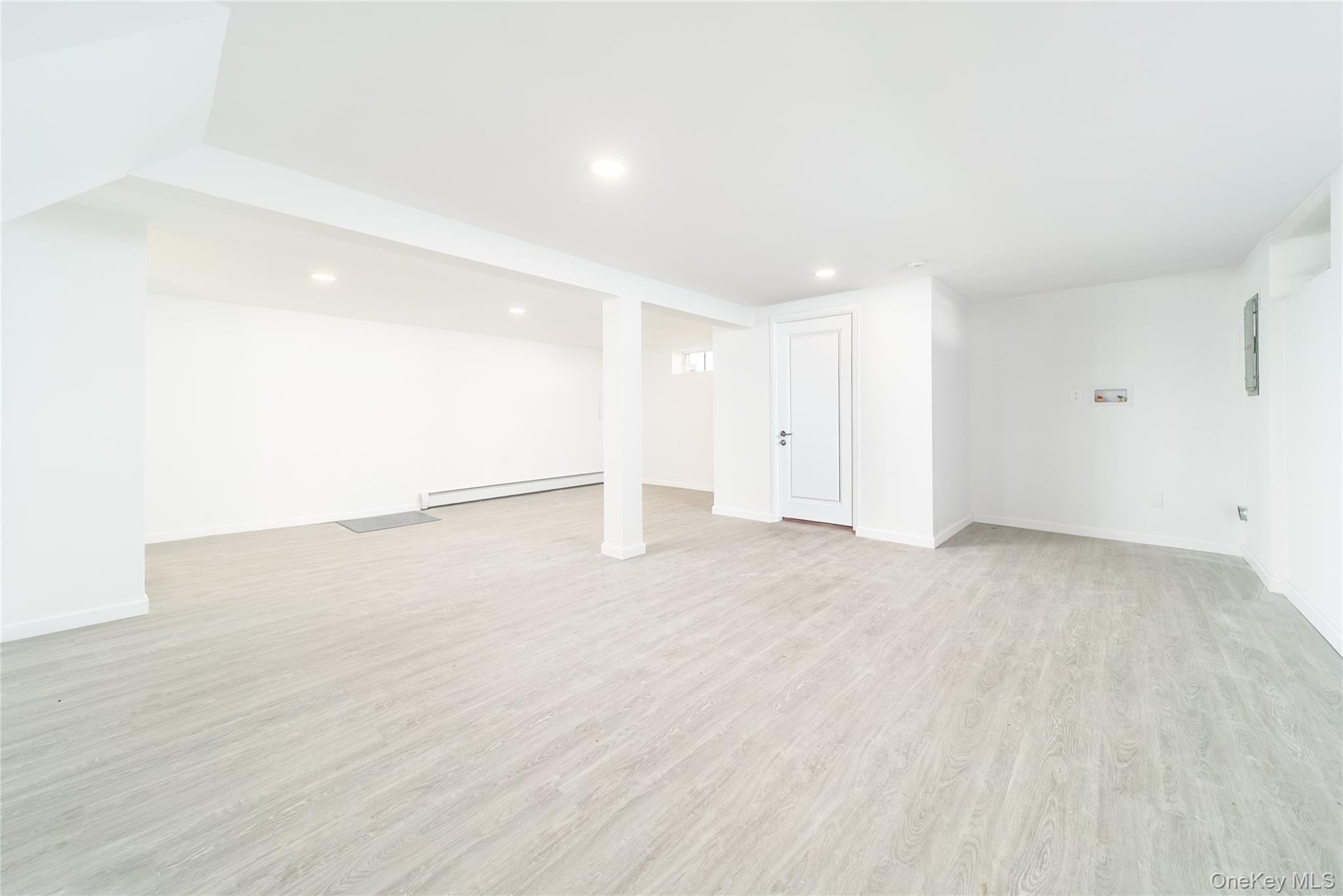 Finished below grade area featuring light wood finished floors, a baseboard heating unit, and recessed lighting
