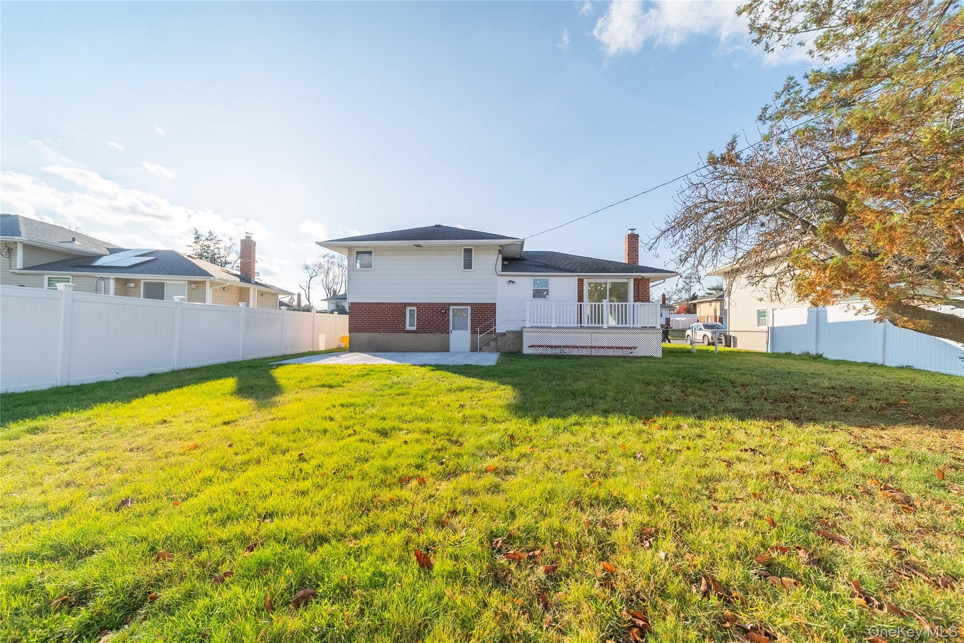 Back of house featuring a fenced backyard, a chimney, brick siding, and a deck
