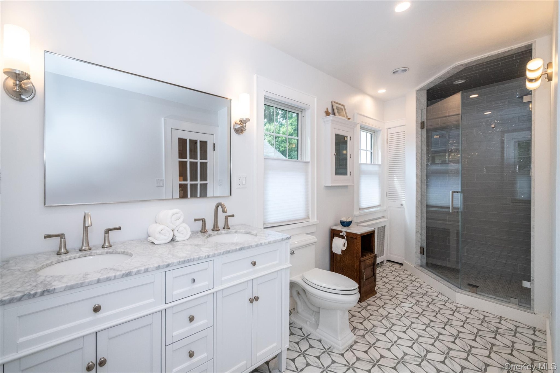 Primary bath features double-vanity sinks, gorgeous new tiling and glass shower