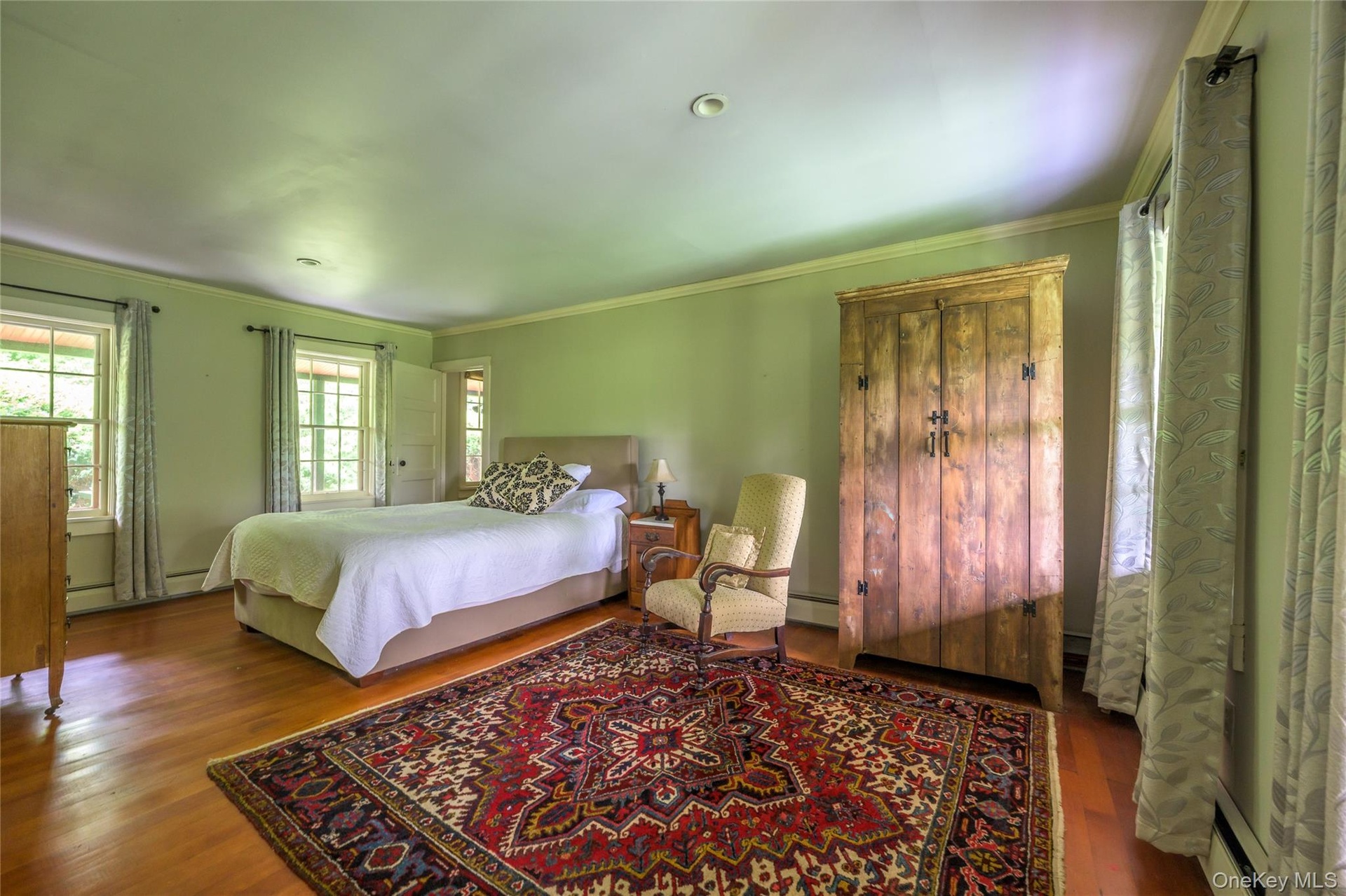 Bedroom featuring wood finished floors, ornamental molding, and a baseboard heating unit