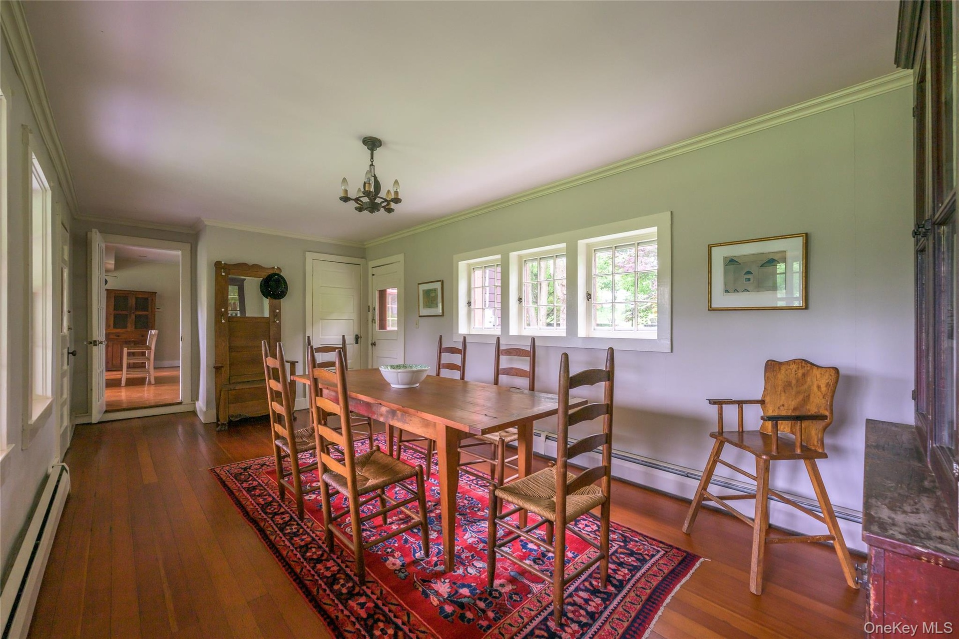 Dining space with a baseboard heating unit, baseboard heating, dark wood-type flooring, and crown molding