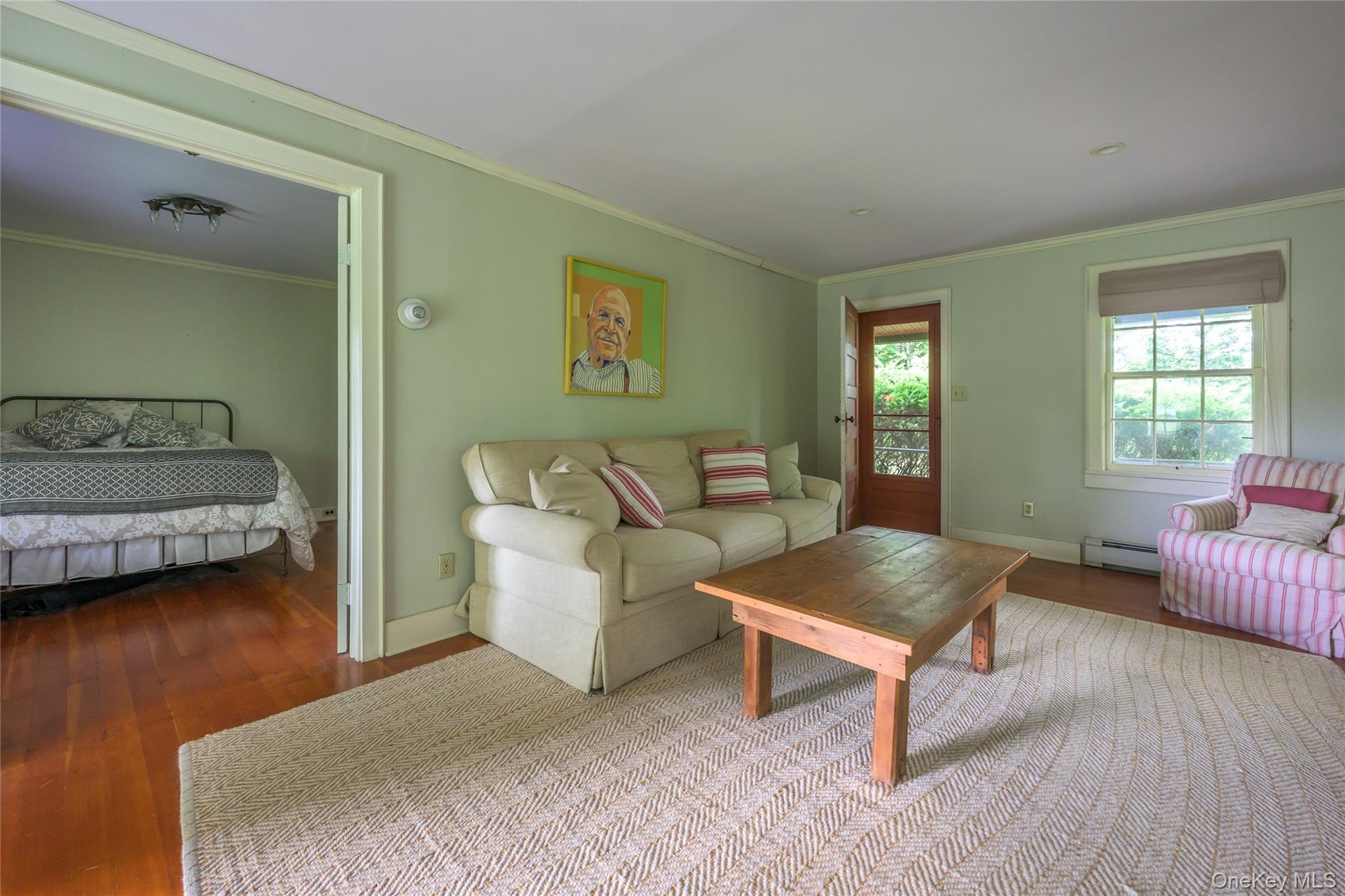 Living room featuring a baseboard heating unit, wood finished floors, and ornamental molding