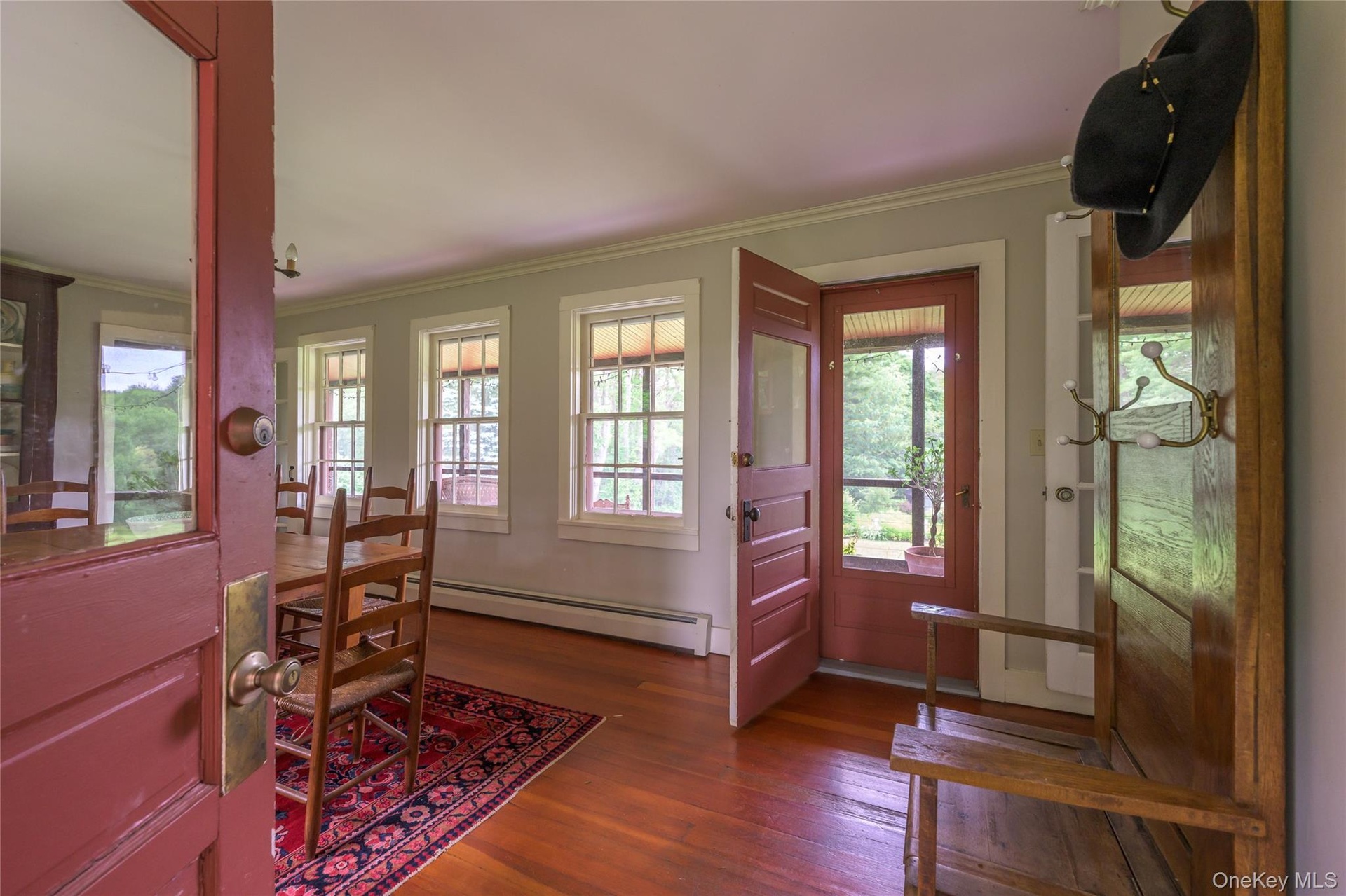 Foyer entrance with baseboard heating, crown molding, wood finished floors, and plenty of natural light