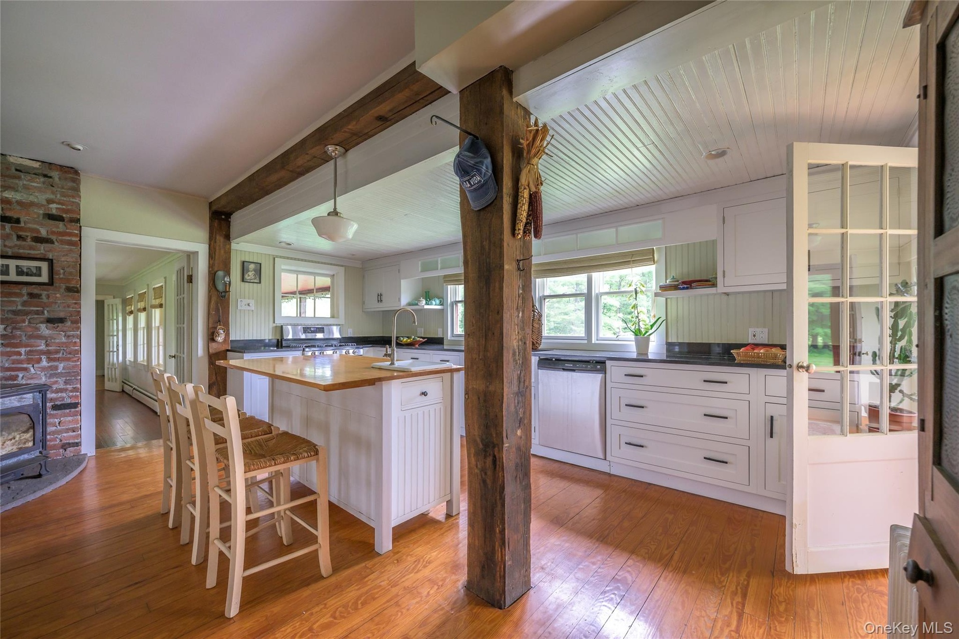 Kitchen featuring dishwasher, light wood finished floors, white cabinetry, decorative light fixtures, and a kitchen bar