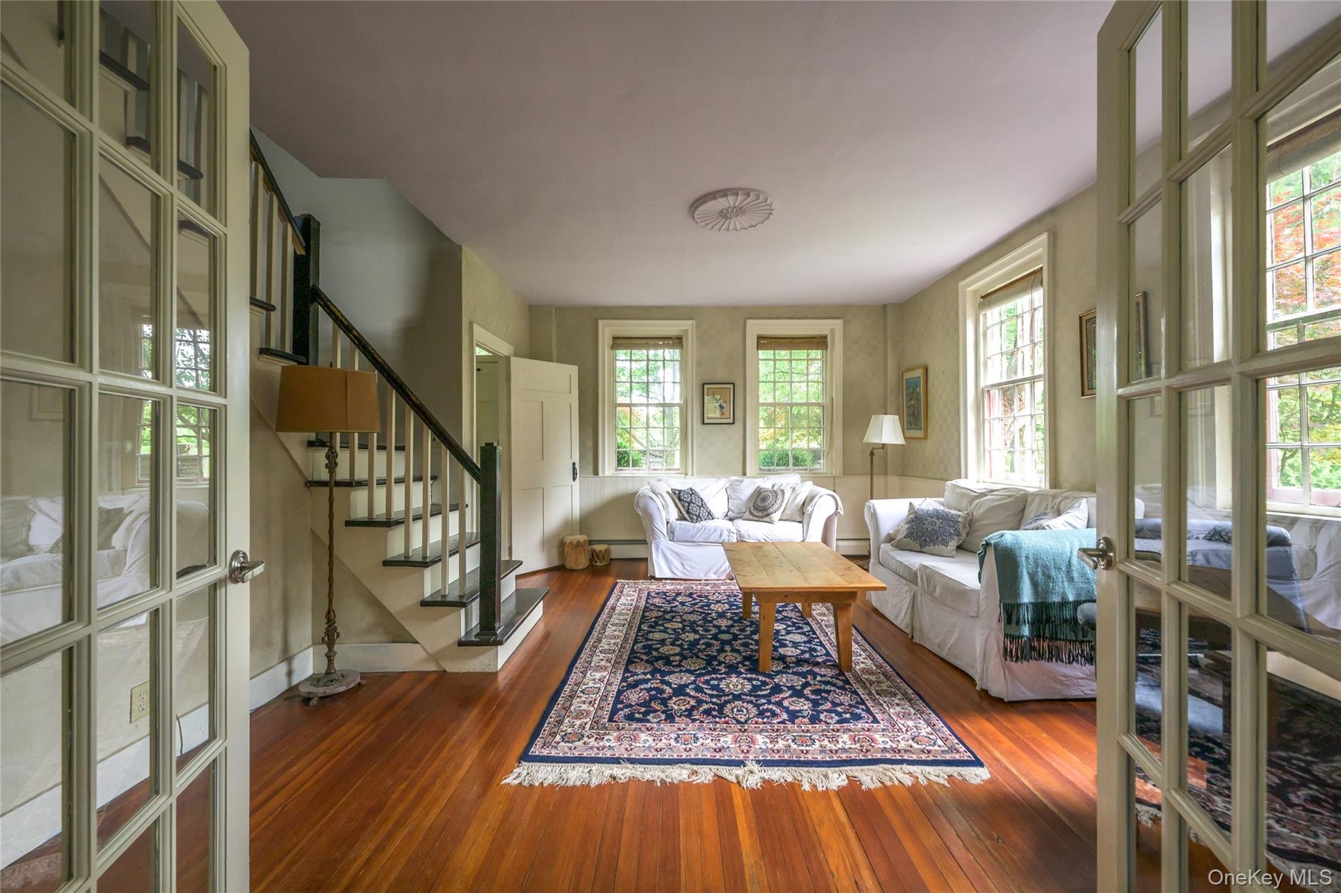 Living area with stairway, wood finished floors, baseboard heating, and a baseboard radiator