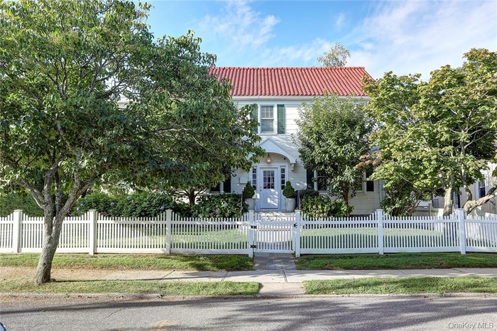 View of front of property with a tiled roof, a gate, and a fenced front yard