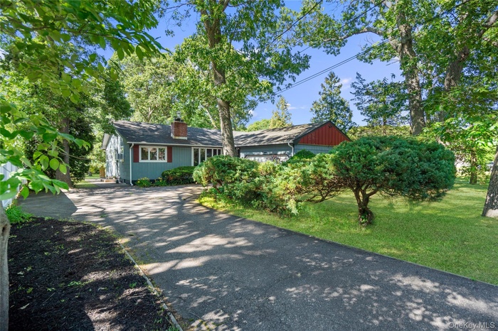 Paved driveway leading to a residence featuring blue siding and red shutters