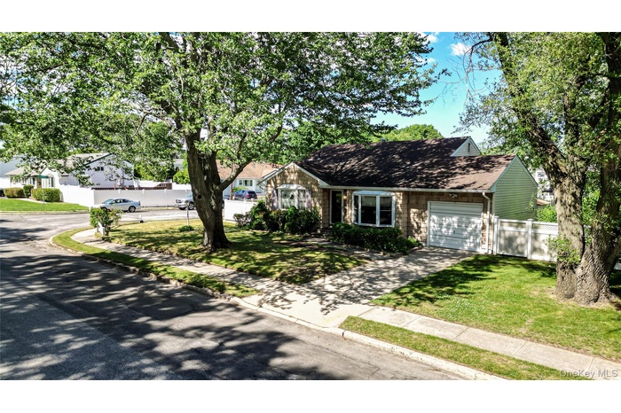 Welcome Home! Split Level style home featuring cedar shake impression siding, brown shingle roof, single car attached garage, driveway, sidewalk and m