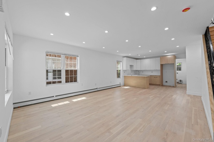 Open-concept living space featuring light wood-finish flooring, recessed lighting, and white baseboards