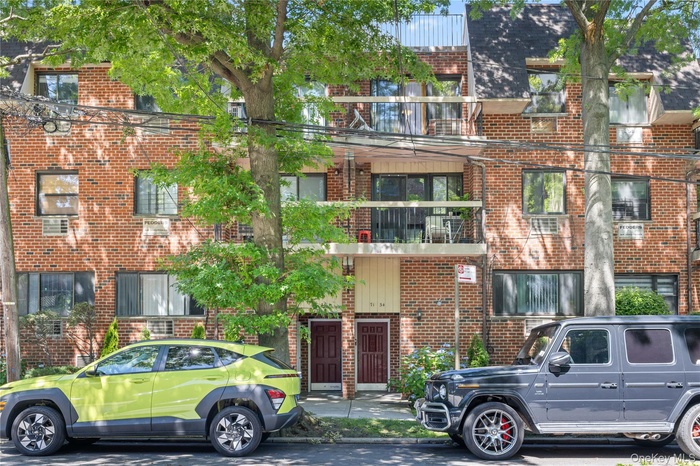 Brick facade building featuring multiple balconies and mature trees