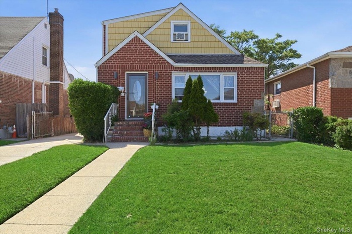 Brick and shingle exterior featuring a prominent front lawn, concrete pathway, and a paved driveway
