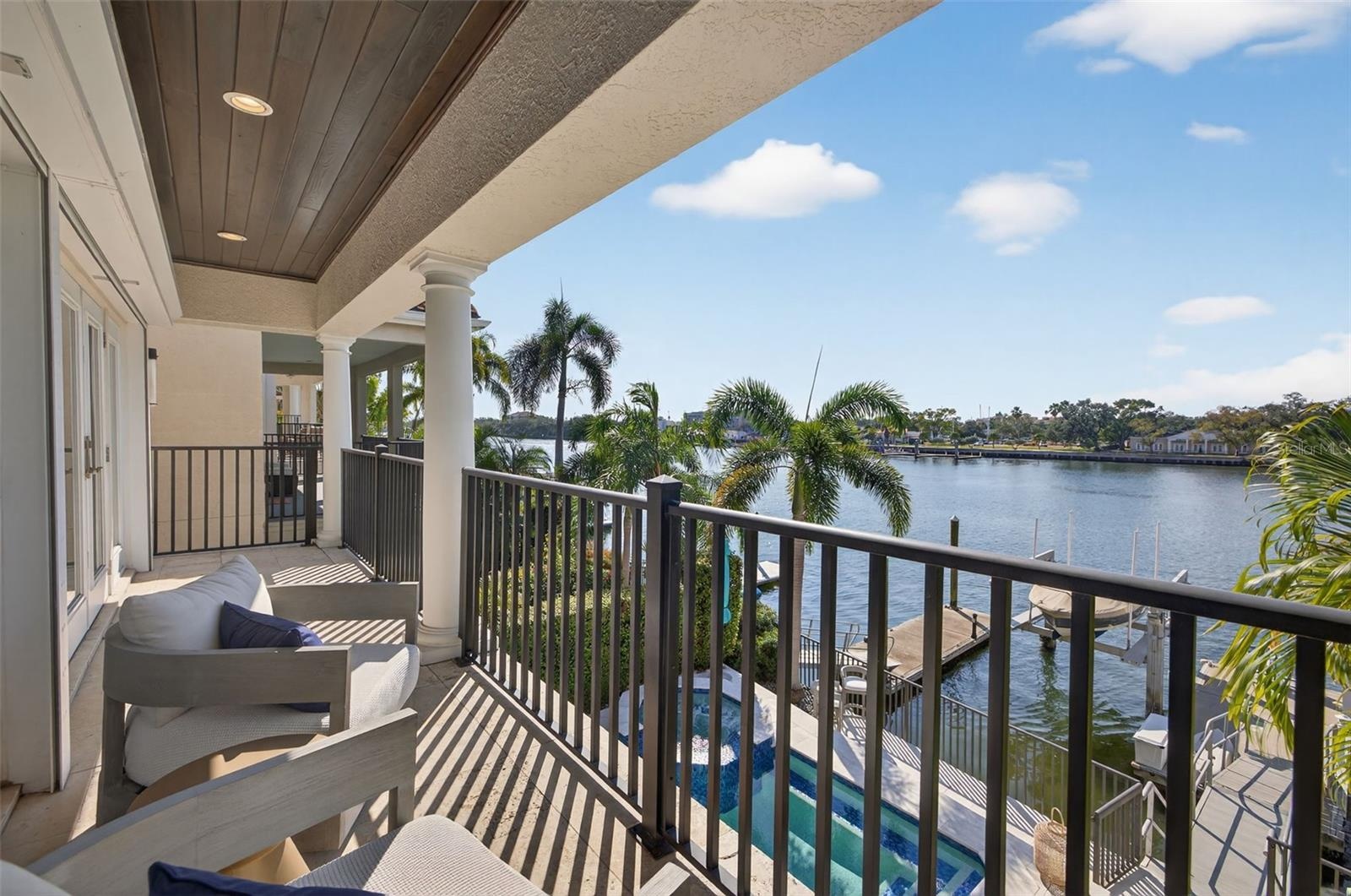 Private primary balcony with captivating views of the pool, deep-water canal, and dock.