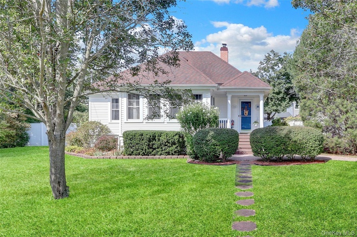 Two-story residence featuring white siding, a covered entry porch, and a brown shingled roof