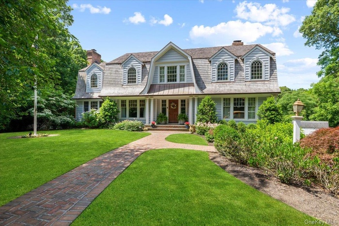 Gabled-roof residence featuring light-toned siding and multiple dormer windows