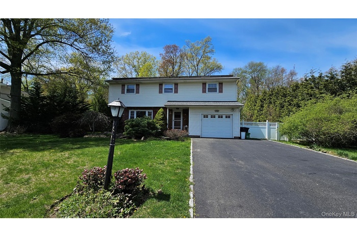 New City Colonial with large driveway and a tree lined street
