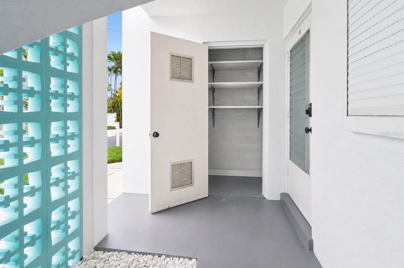 Outdoor Storage closet and area to park bicycles on the gravel behind the blue wall