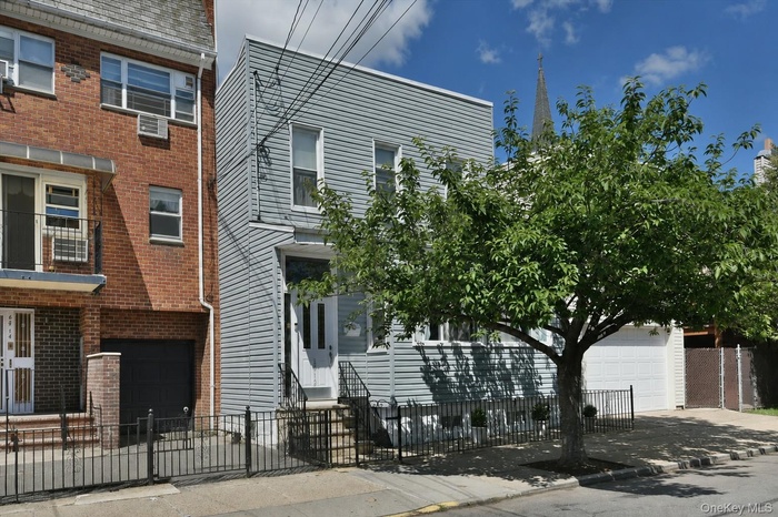 Two-story residence featuring light gray siding and a white entry door