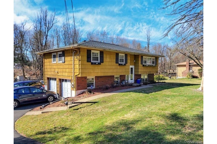 Split-level residence featuring yellow siding and black louvered shutters