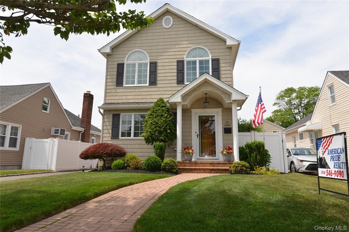 Two-story residence featuring light-colored siding and dark shutters